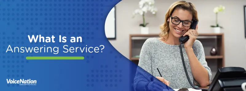 Smiling woman sitting at desk on phone.