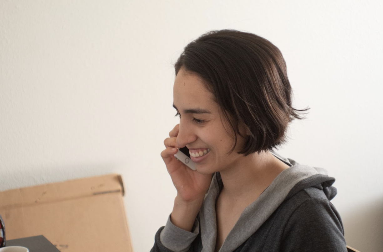 Woman with brown hair smiling while she talks on the phone